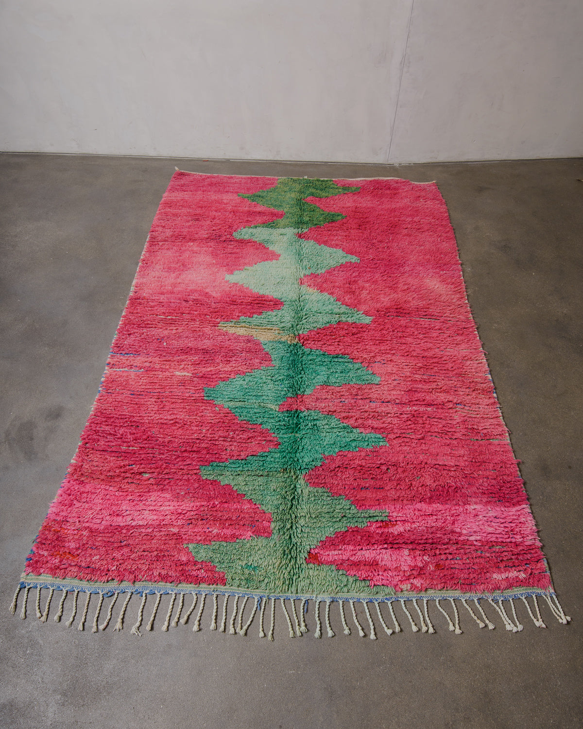 Pink and green patterned rug on a concrete floor